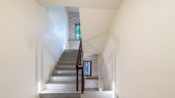 Eine Treppe mit einer Steinmauer und einem Fenster mit dekorativem Gitter.