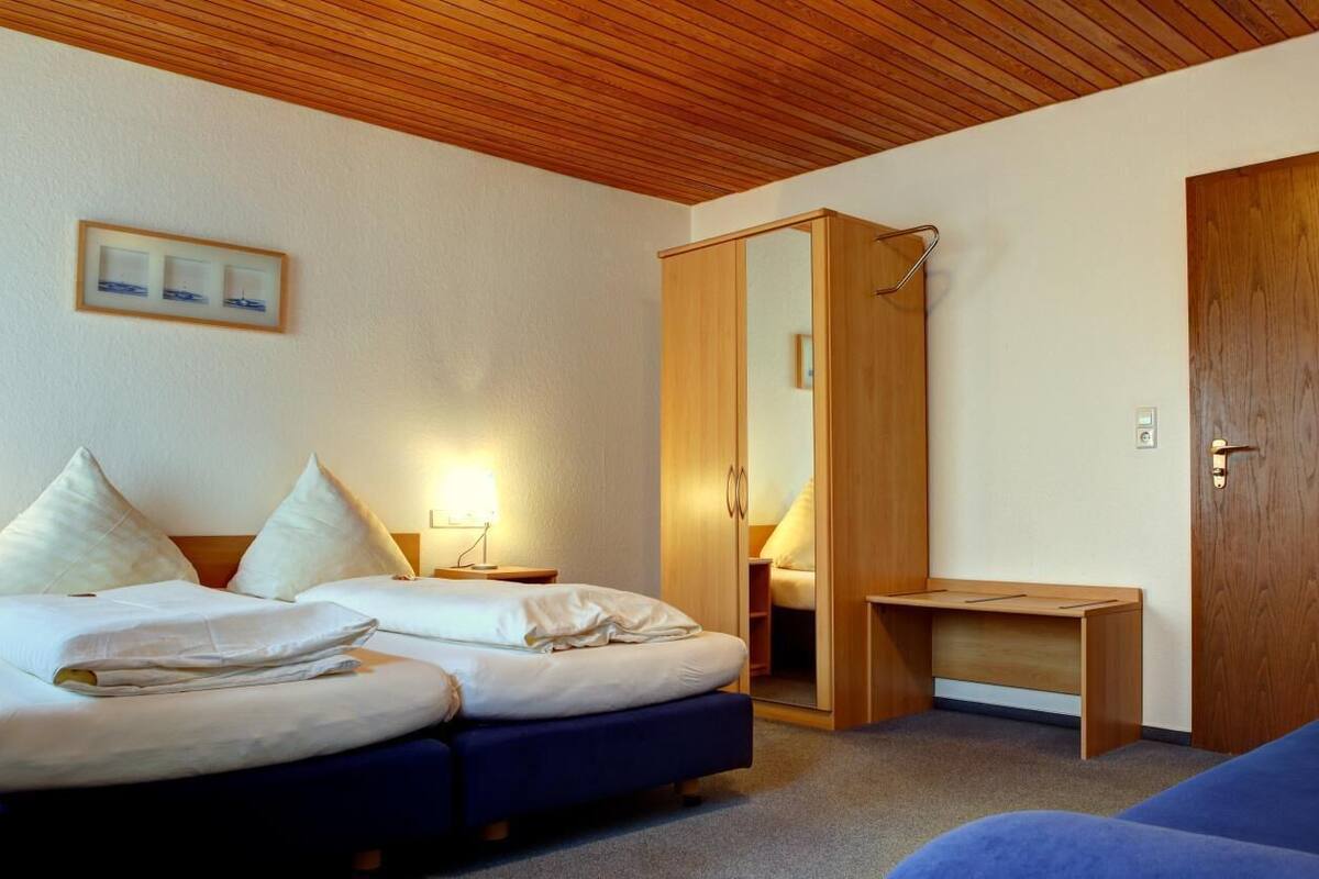 A hotel room with a bed, a desk, a wardrobe, and a door.