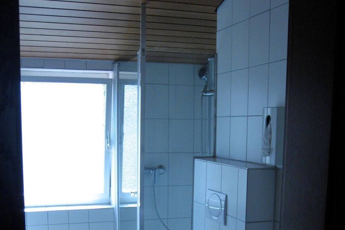 A small, compact bathroom with a toilet, a shower, and a sink.