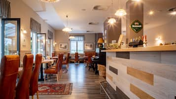 A restaurant with wooden flooring, red chairs, and a bar area with a sign reading "Bernard".