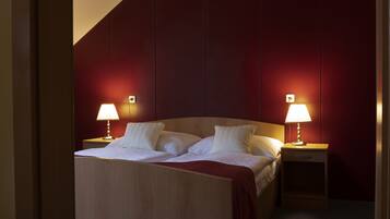 Una habitación de hotel con una cama, dos mesitas de noche y dos lámparas.