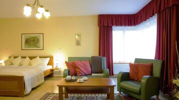 A hotel room with a bed, two armchairs, a coffee table, and a window with curtains.
