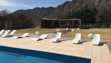 Una piscina al aire libre, sillones reclinables de piscina