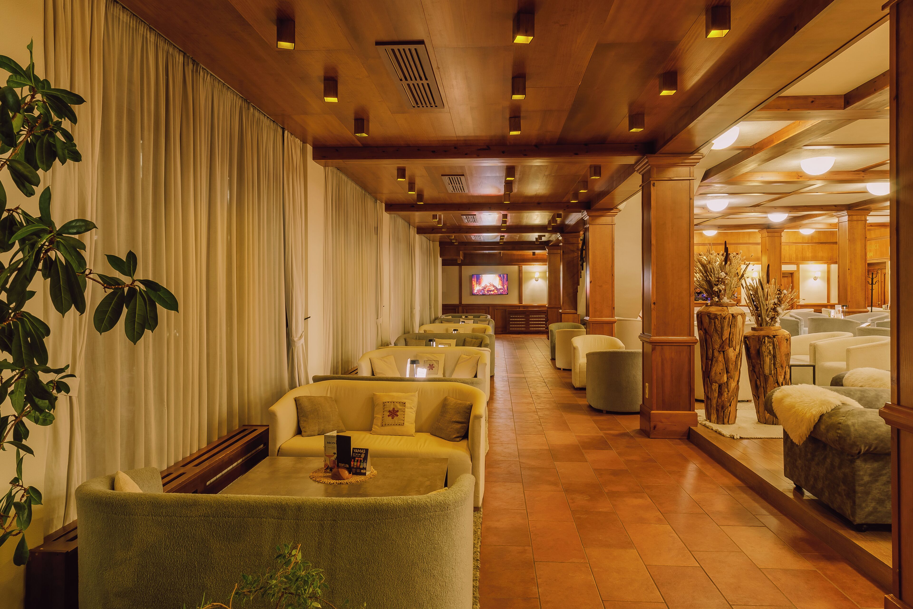 Un hall d’hôtel doté de plusieurs espaces salon, d’un écran de télévision et d’un revêtement de sol en bois.