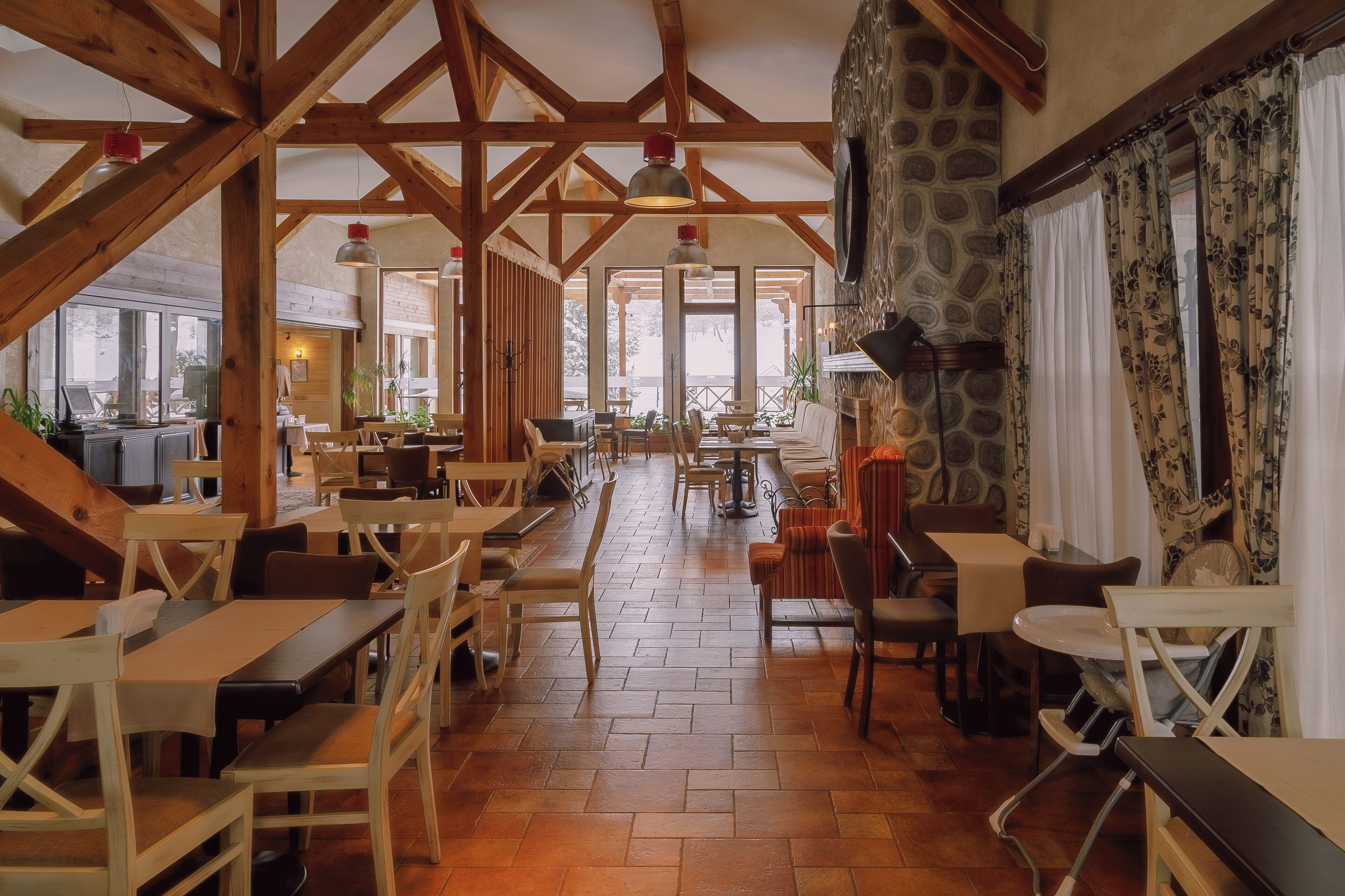 Un comedor amplio con vigas de madera, mesas y sillas.