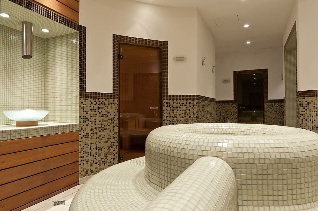 Un baño moderno con una bañera grande y curvada, paneles de madera y paredes de mosaico.