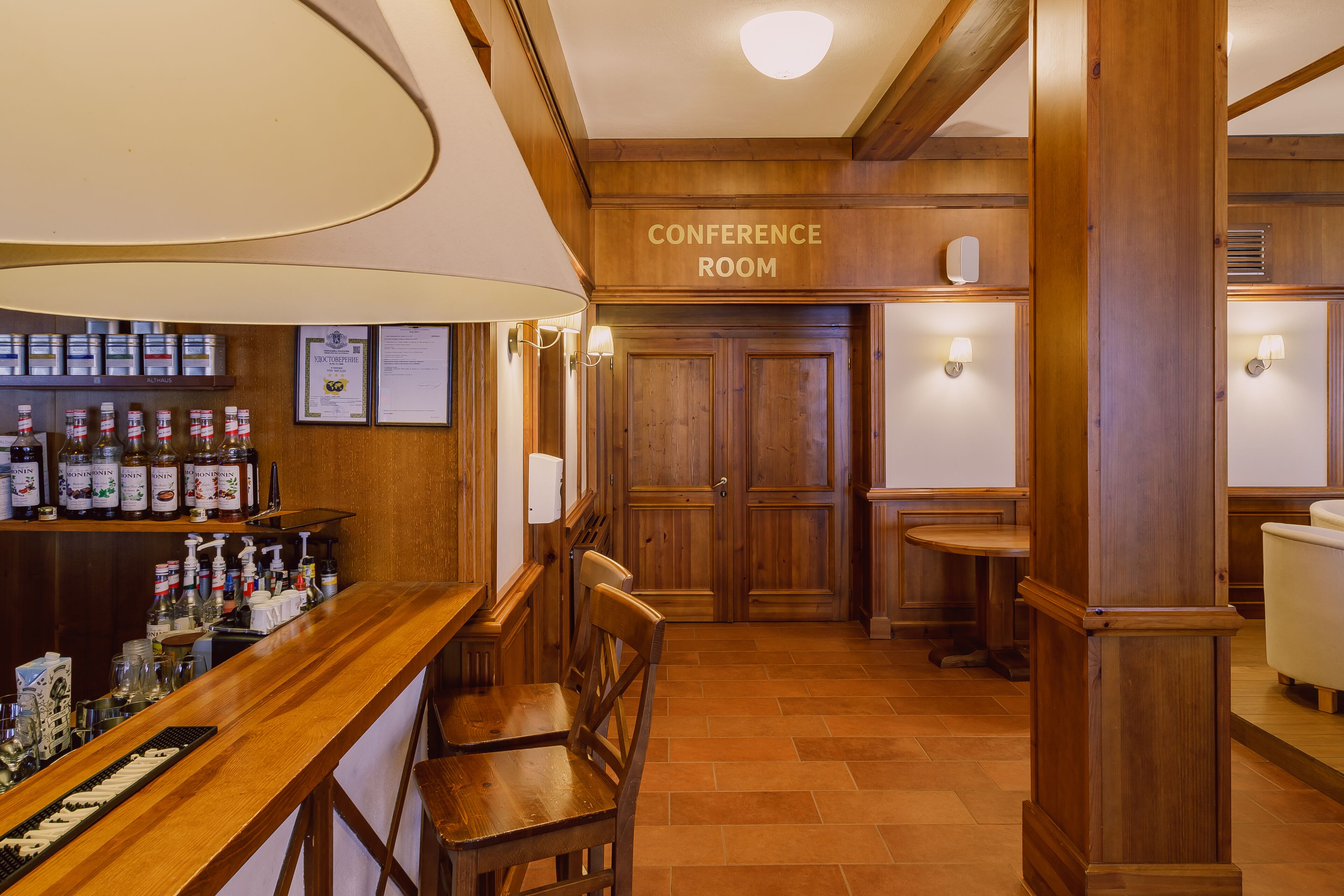 A conference room with wooden paneling, a bar area with bottles, and a white chair.