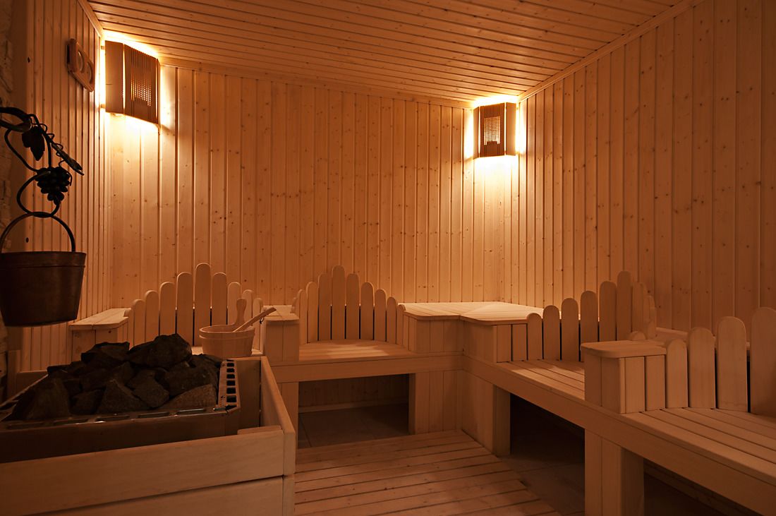 Una sauna con bancos de madera, un cubo y un montón de piedras.