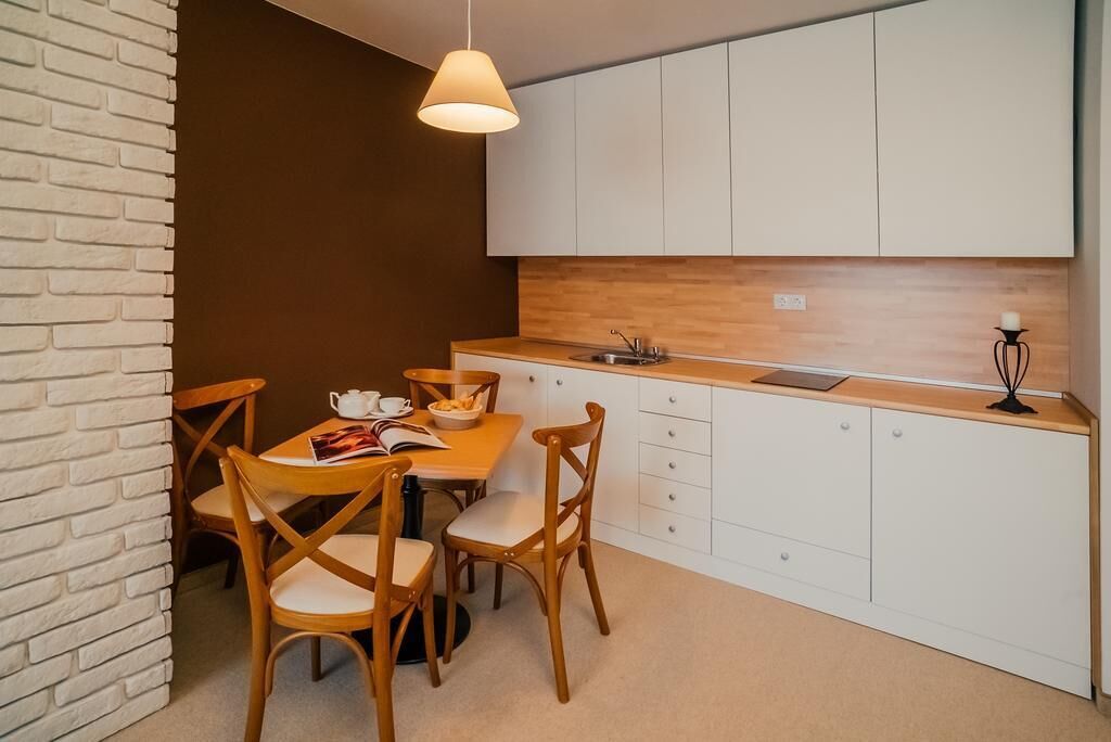 Cocina compacta con armarios blancos, encimera de madera y lámpara colgante.