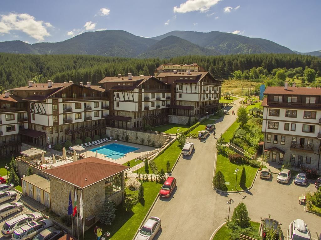 A hotel with multiple buildings, a swimming pool, and a parking area.