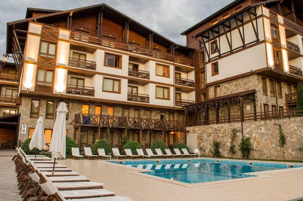 A hotel with a pool area, multiple balconies, and outdoor seating.