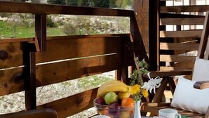 Eine Holzterrasse mit einem für das Frühstück gedeckten Tisch, mit Blick auf eine gebirgige Landschaft.
