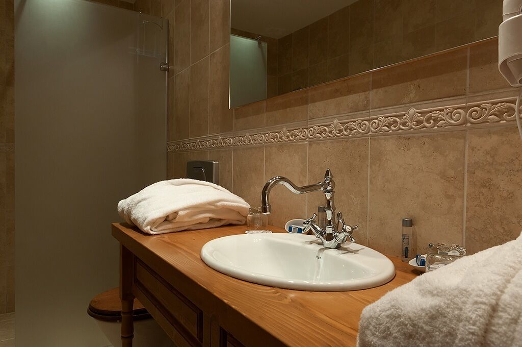 A bathroom with a wooden vanity, a white sink, and a mirror.