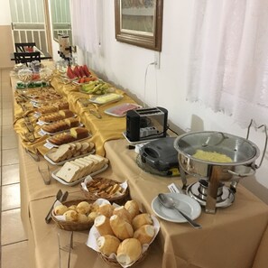 A buffet table with various food items and utensils. - Apartementos Vista da Serra (Ouro Branco)