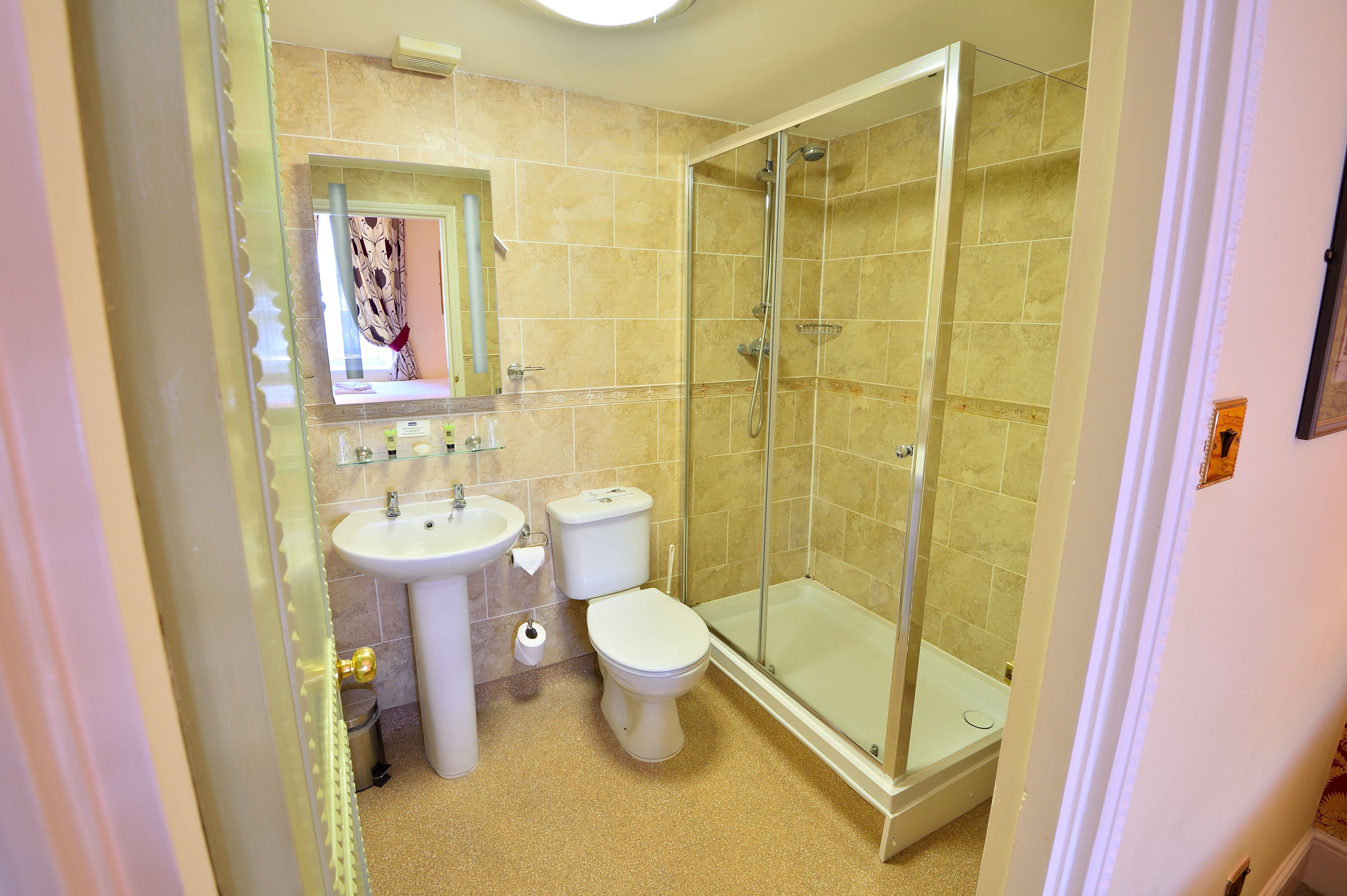 A bathroom with a glass-enclosed shower, a sink, and a toilet.