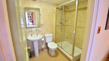 A bathroom with a glass-enclosed shower, a sink, and a toilet.