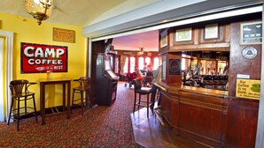 A cozy interior with a bar area, wooden furniture, and a vintage sign reading "Camp Coffee". - The Angel Hotel (Coleford)