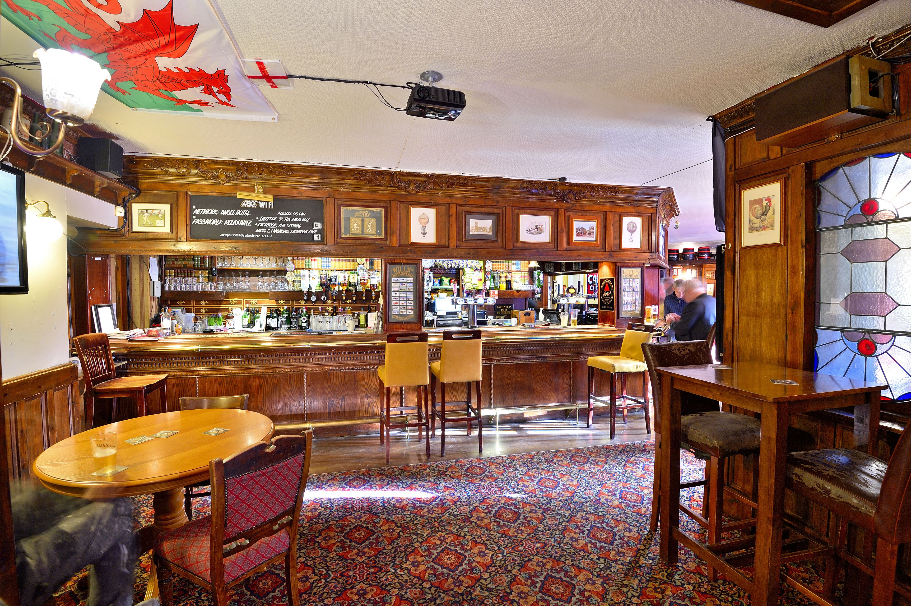 A bar area with wooden furniture, a patterned carpet, and a red dragon flag.