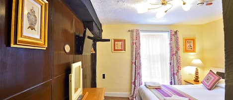 Una habitación de hotel con una cama, un escritorio, un televisor y cortinas.