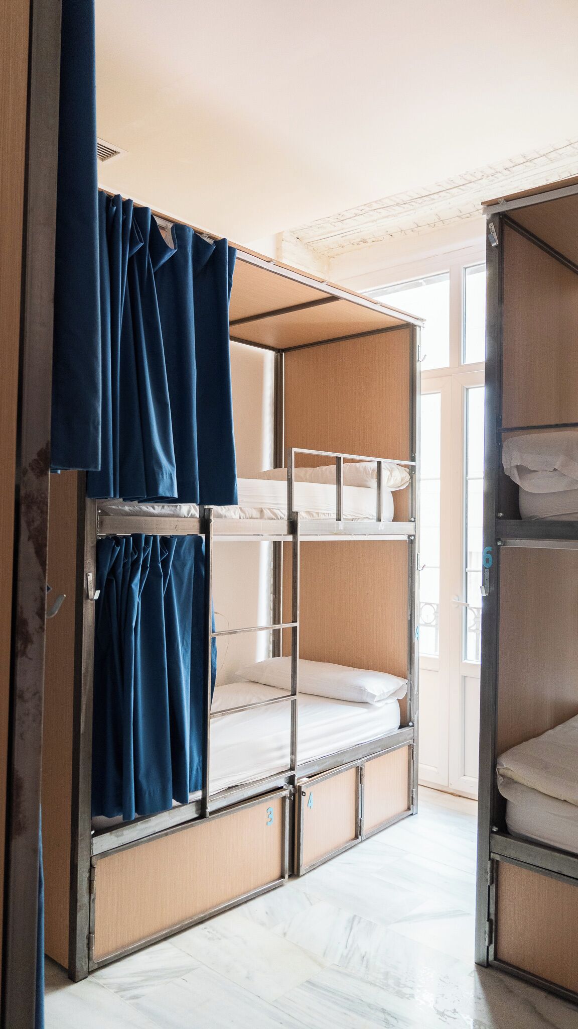 A bunk bed room with curtains, a door, and a tiled floor.