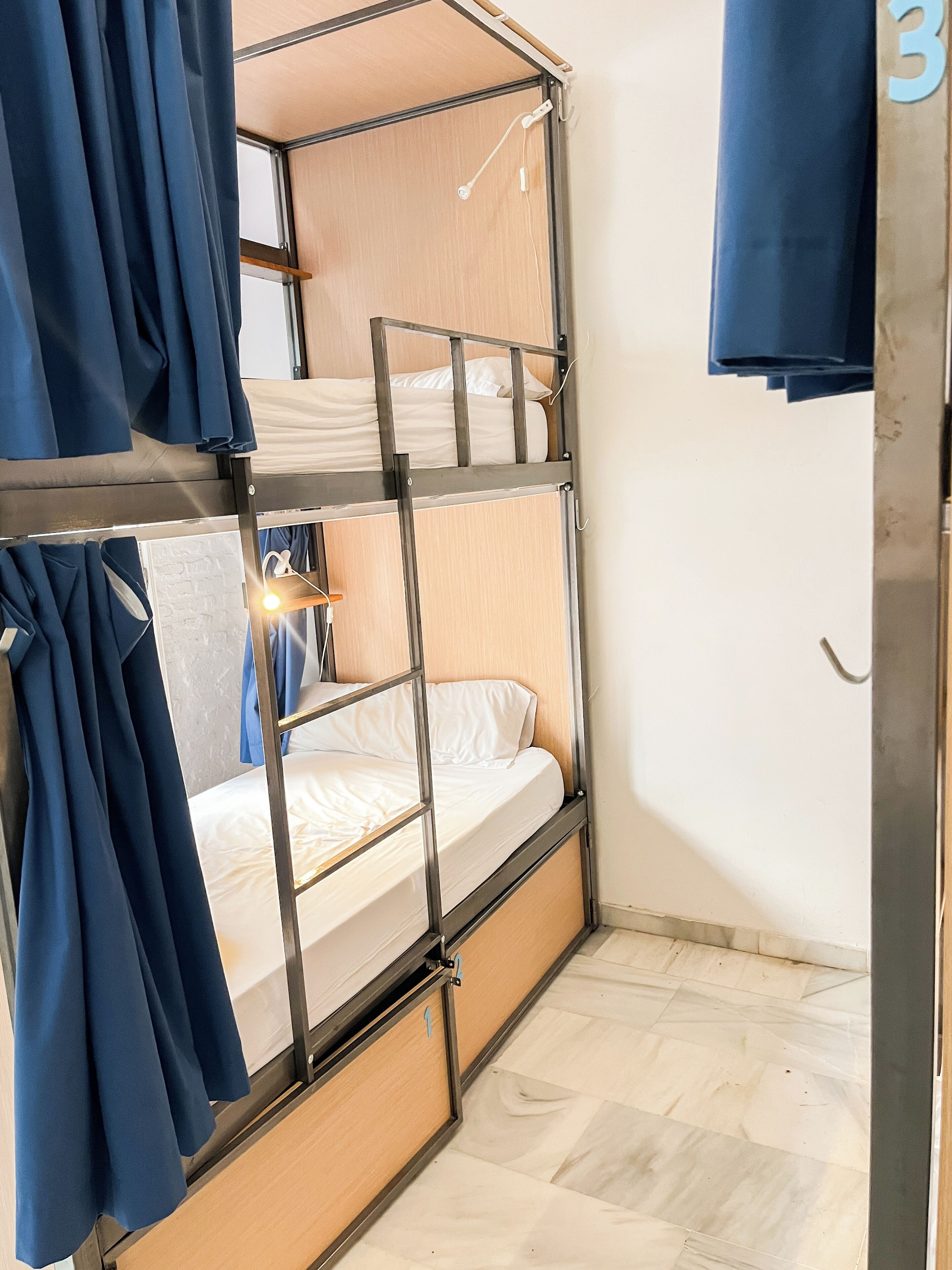 A bunk bed room with curtains, a wooden floor, and a number '3' on the wall.
