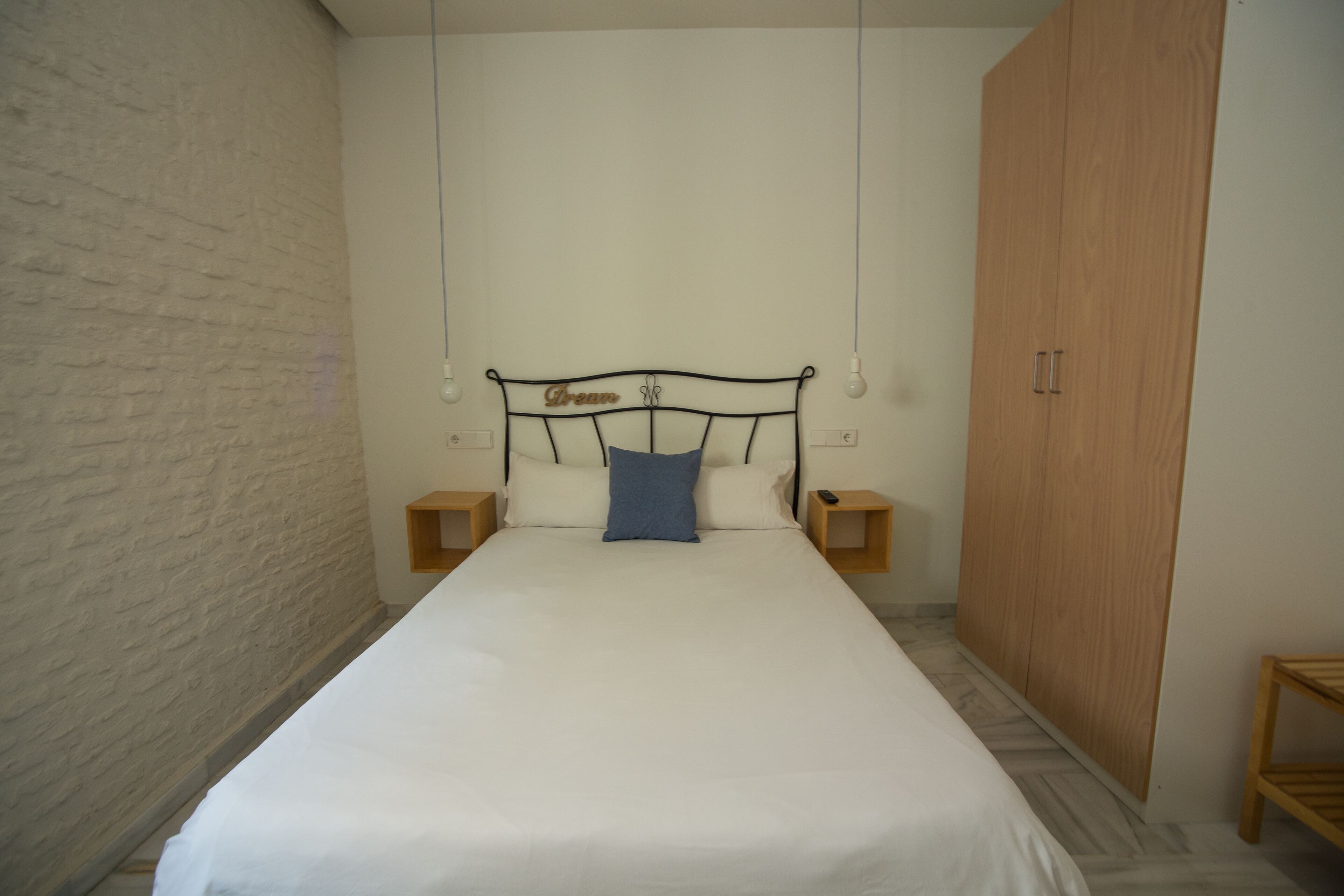 Un dormitorio con cama, un armario de madera y una pared de ladrillo.