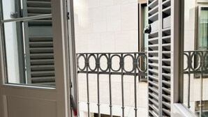 A view from a balcony with a metal railing, a tiled floor, and a white door with a handle. - The Nomad Hostel (Seville)