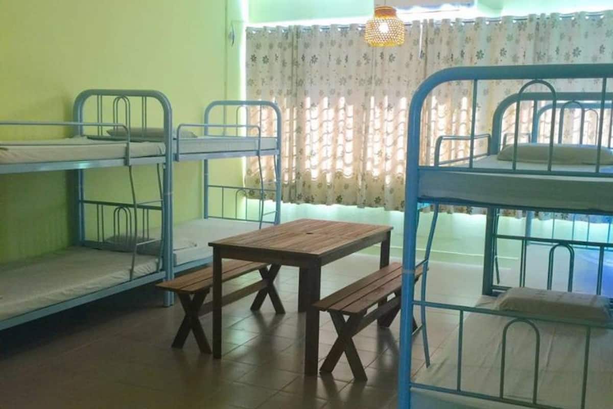 A dormitory room with bunk beds, a wooden table, and benches.