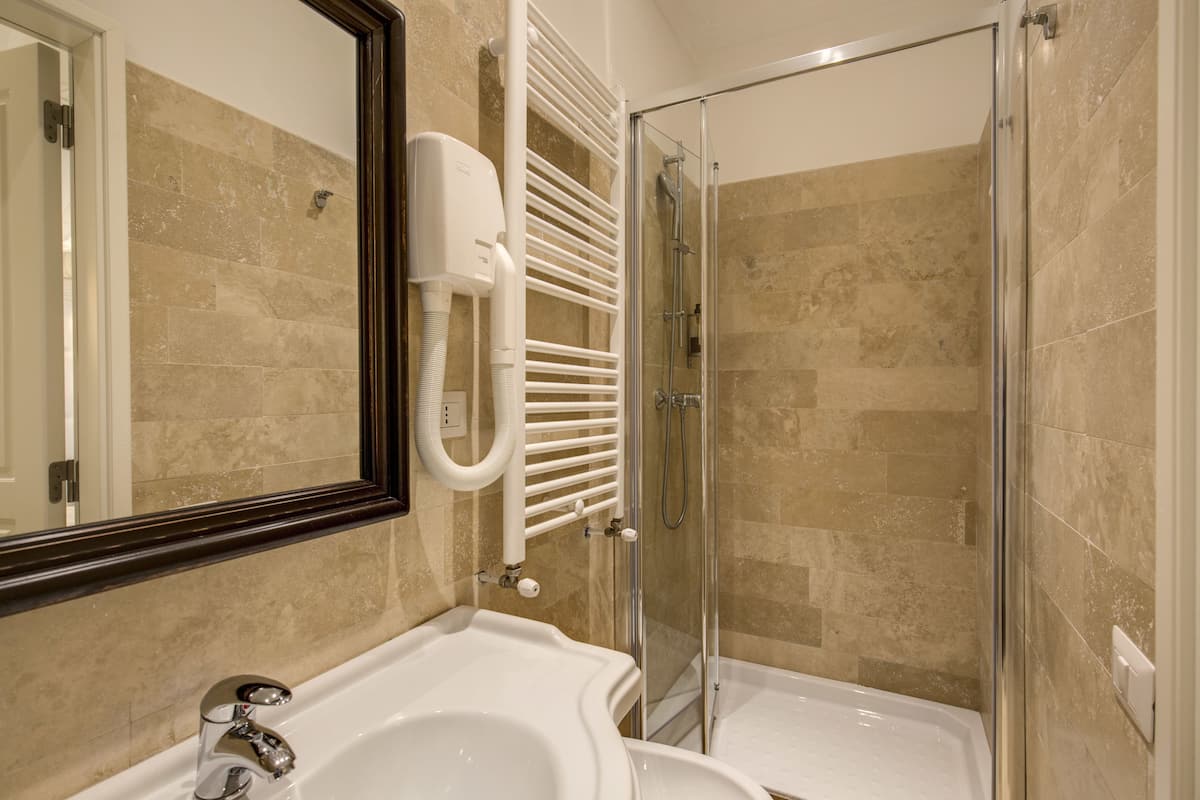A bathroom with a bathtub, a shower, and a hand dryer.