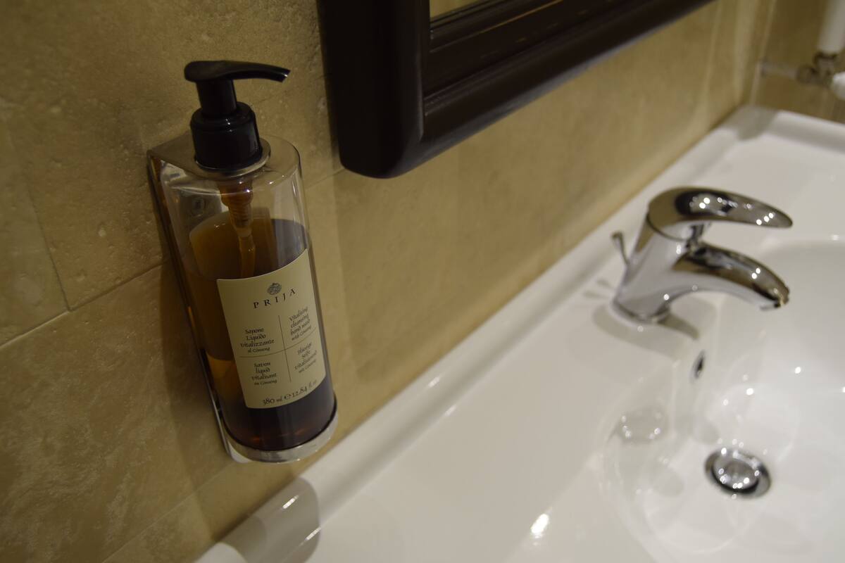 A bathroom with a white sink, a black soap dispenser, and a mirror above the sink.