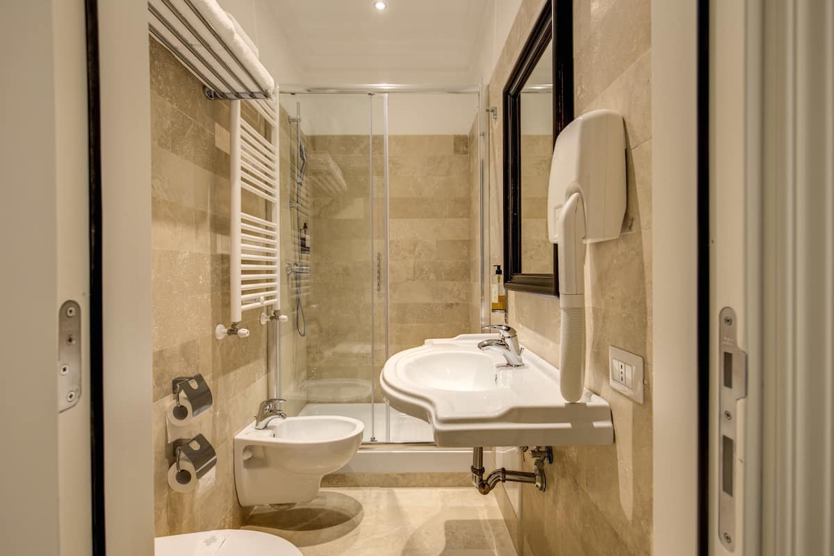 A modern bathroom with a glass-enclosed shower, a bidet, and two sinks.