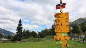 Un indicador direccional en un entorno rural, con senderos que conducen a varios destinos.