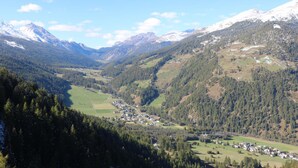 Un paisaje montañoso con un valle y un pequeño pueblo enclavado entre colinas.