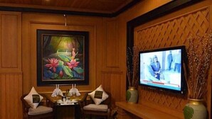 A room with wooden paneling, a painting of flowers, a television, and a small table with chairs. - Shwe Kyun Hotel (Taunggyi)
