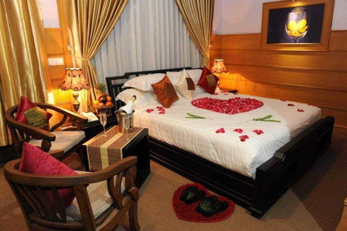 A neatly arranged hotel room with a bed, a chair, a small table, and a lamp.