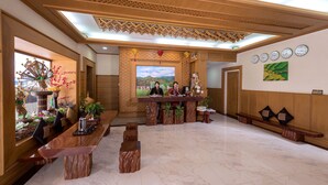 A reception area with a wooden reception desk, a large framed painting, and a clock on the wall. - Shwe Kyun Hotel (Taunggyi)
