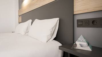 Una habitación de hotel moderna con una cama, una mesita de noche y un panel de control con botones y pantalla.