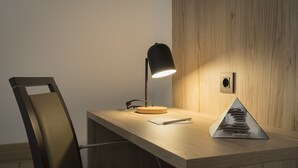 A wooden desk with a modern lamp, a chair, and a pyramid-shaped object on the desk. - Alda Centro Gijón (Gijon)