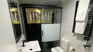 A compact bathroom with a white sink, a toilet, and a shower area. - Alda Centro Gijón (Gijon)