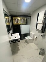 Un baño pequeño con un lavamanos blanco, un inodoro y una zona de ducha.