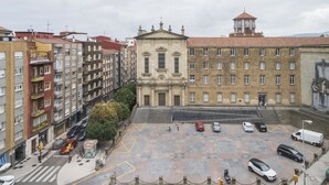 A multi-story building with a central courtyard, surrounded by parked cars and a few pedestrians. - Alda Centro Gijón (Gijon)