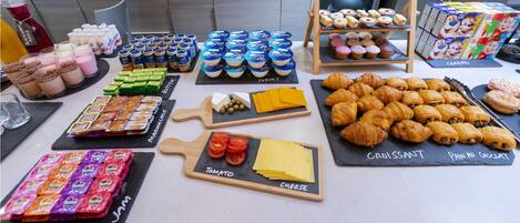 A variety of food items including pastries, cheese, and packaged snacks on a table.