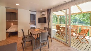 Ein modernes Zimmer mit einem Holztisch, Stühlen, einem Bett, einem Fernseher und einem Balkon mit Seeblick.