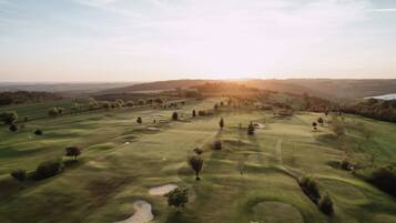 A golf course with rolling hills, trees, and sand bunkers.