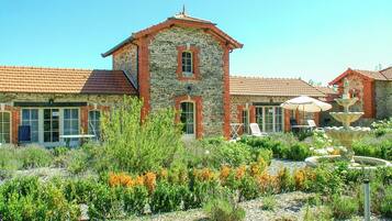 A stone building with a tiled roof, a fountain, and outdoor seating.