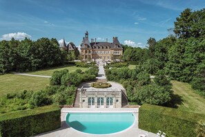 Une vaste demeure historique dotée d’un jardin à la française, d’une piscine centrale et d’une disposition symétrique.