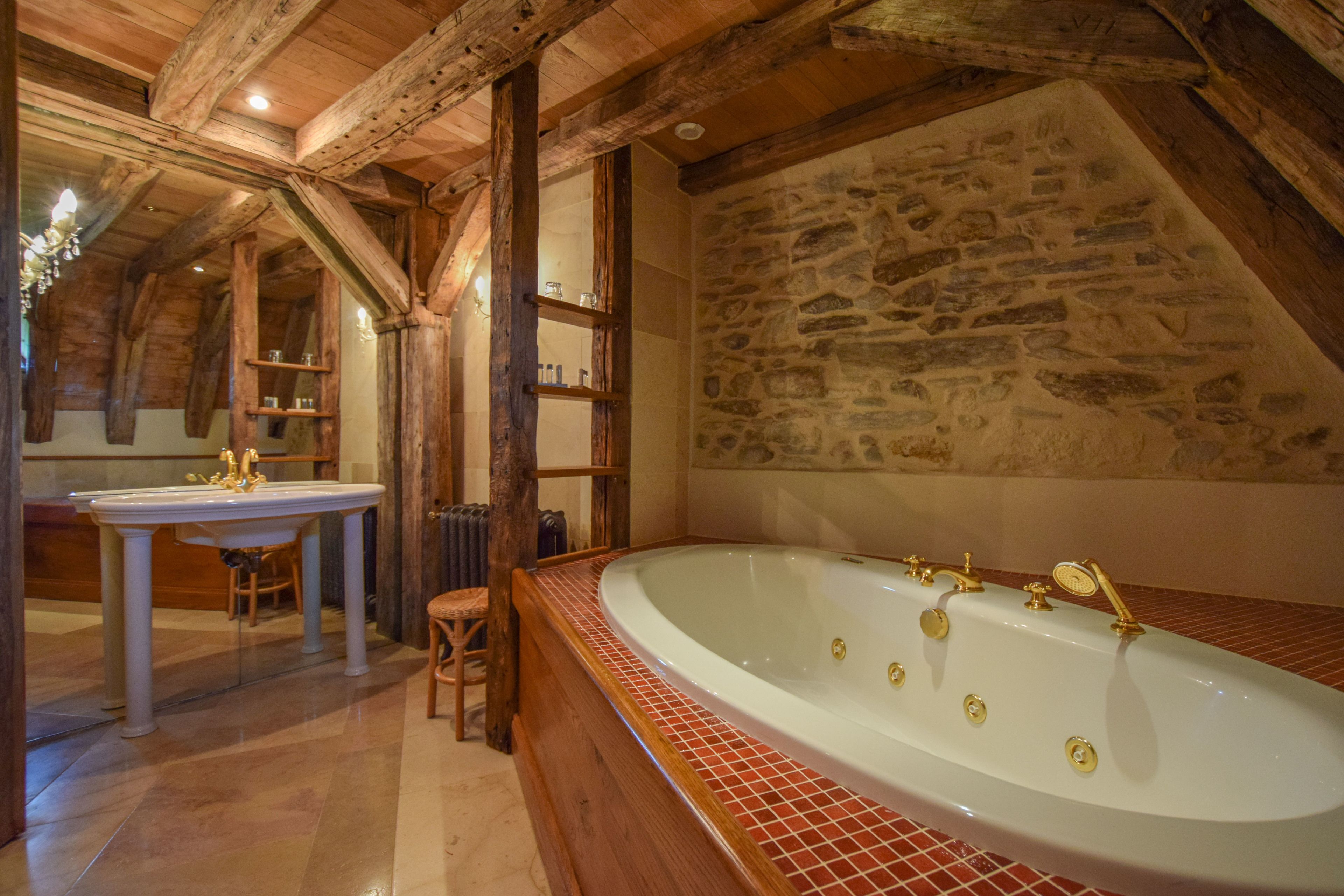 A bathroom with a stone wall, a bathtub, and a sink.