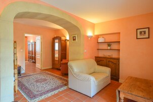 Una sala de estar con un sofá blanco, una mesa de madera, un tapete estampado y un mueble de madera.