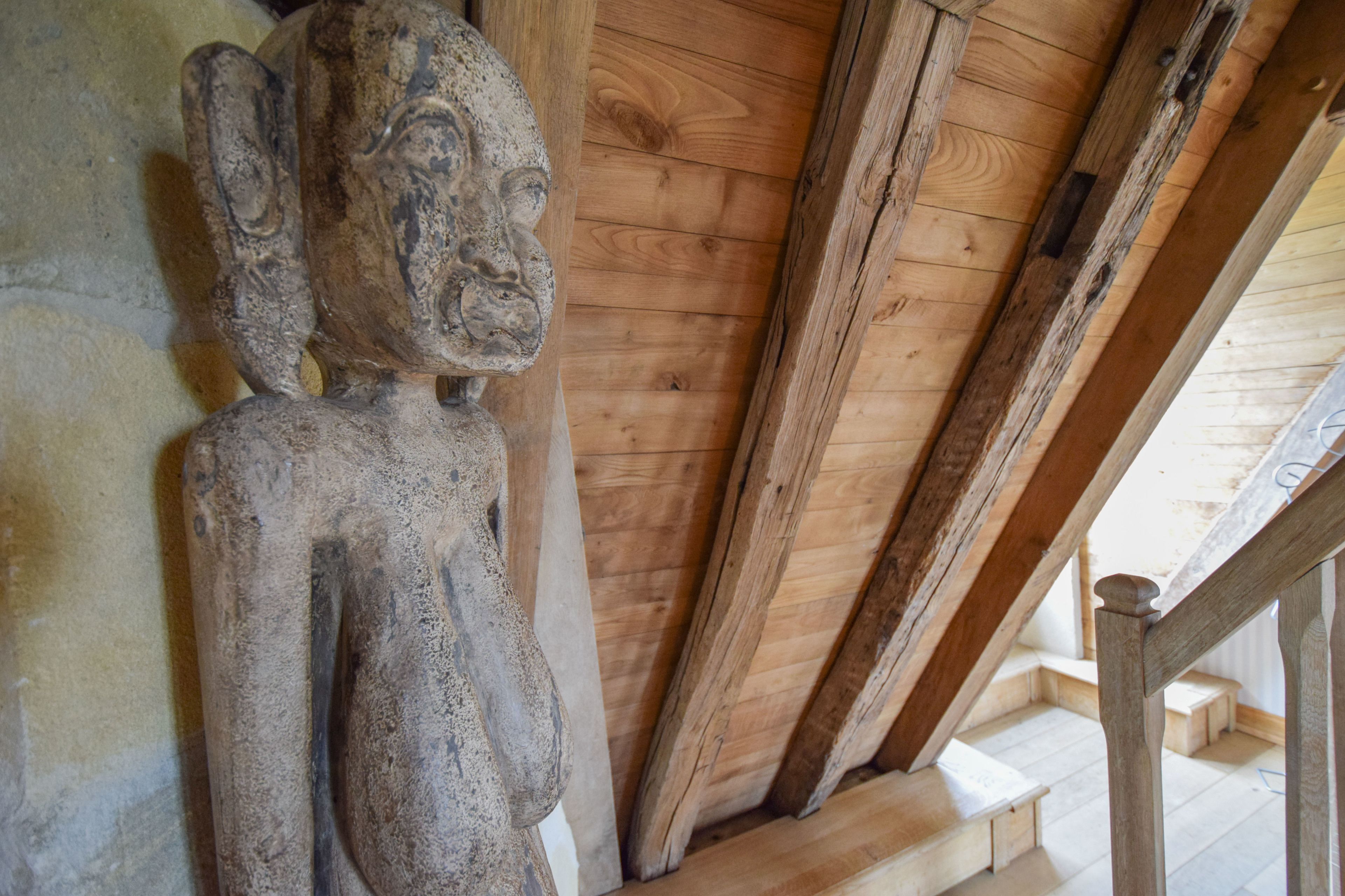 Techo de madera con vigas a la vista y una escultura de piedra.