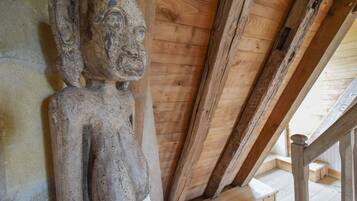 Techo de madera con vigas a la vista y una escultura de piedra.